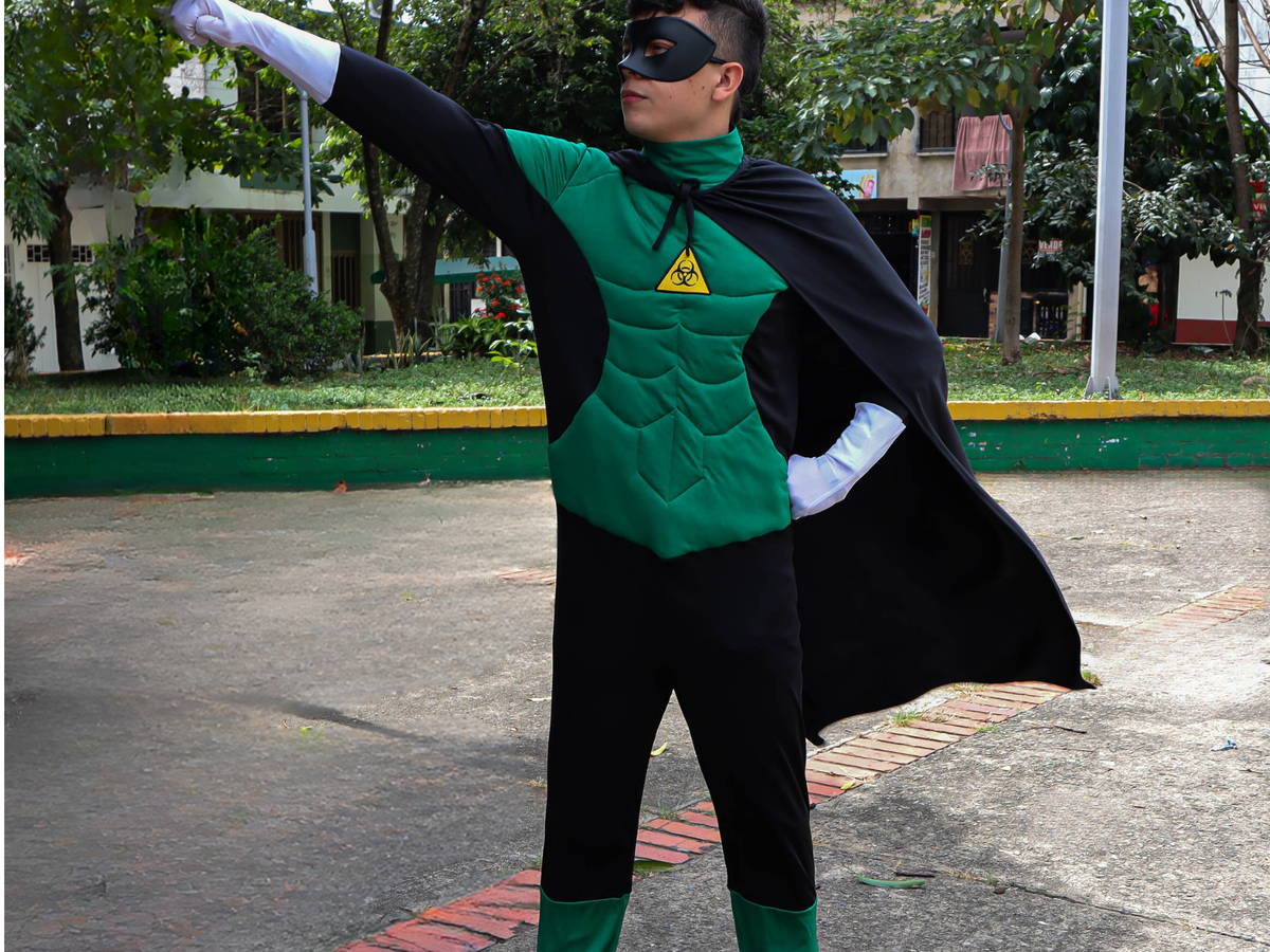 Facilitador caracterizado como un superhéroe verde con capa, en la zona exterior de una planta.