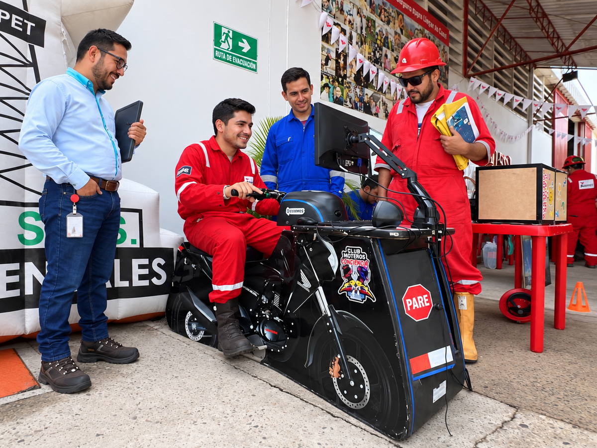 Trabajador en overol rojo montado sobre el simulador de motocicleta mientras varios compañeros siguen la pantalla, durante una jornada en las instalaciones de un cliente.
