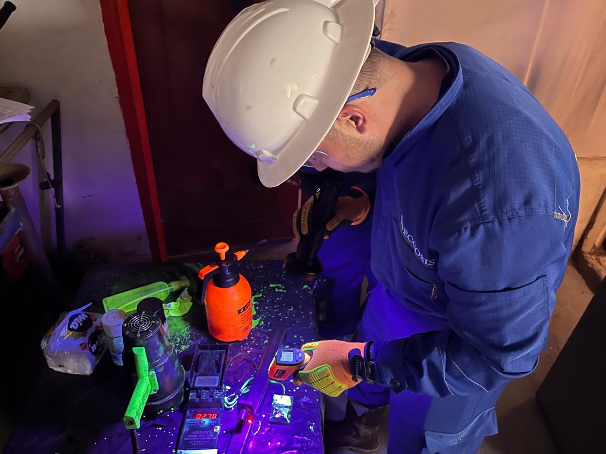 Inspector aplicando revelador sobre una pieza metálica bajo luz ultravioleta, que hace visibles las indicaciones en tonos fluorescentes.