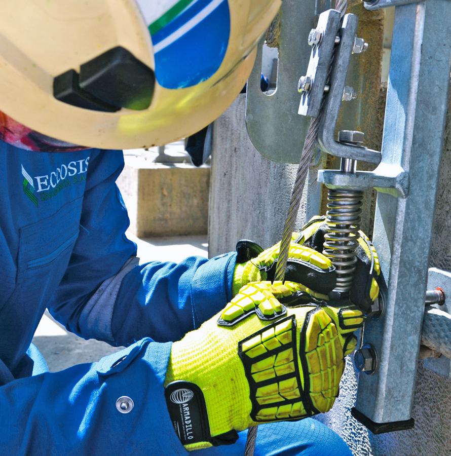 Técnico ajusta el sistema tensor inferior, con resorte y cable de acero, sobre el peldaño de la escalera.