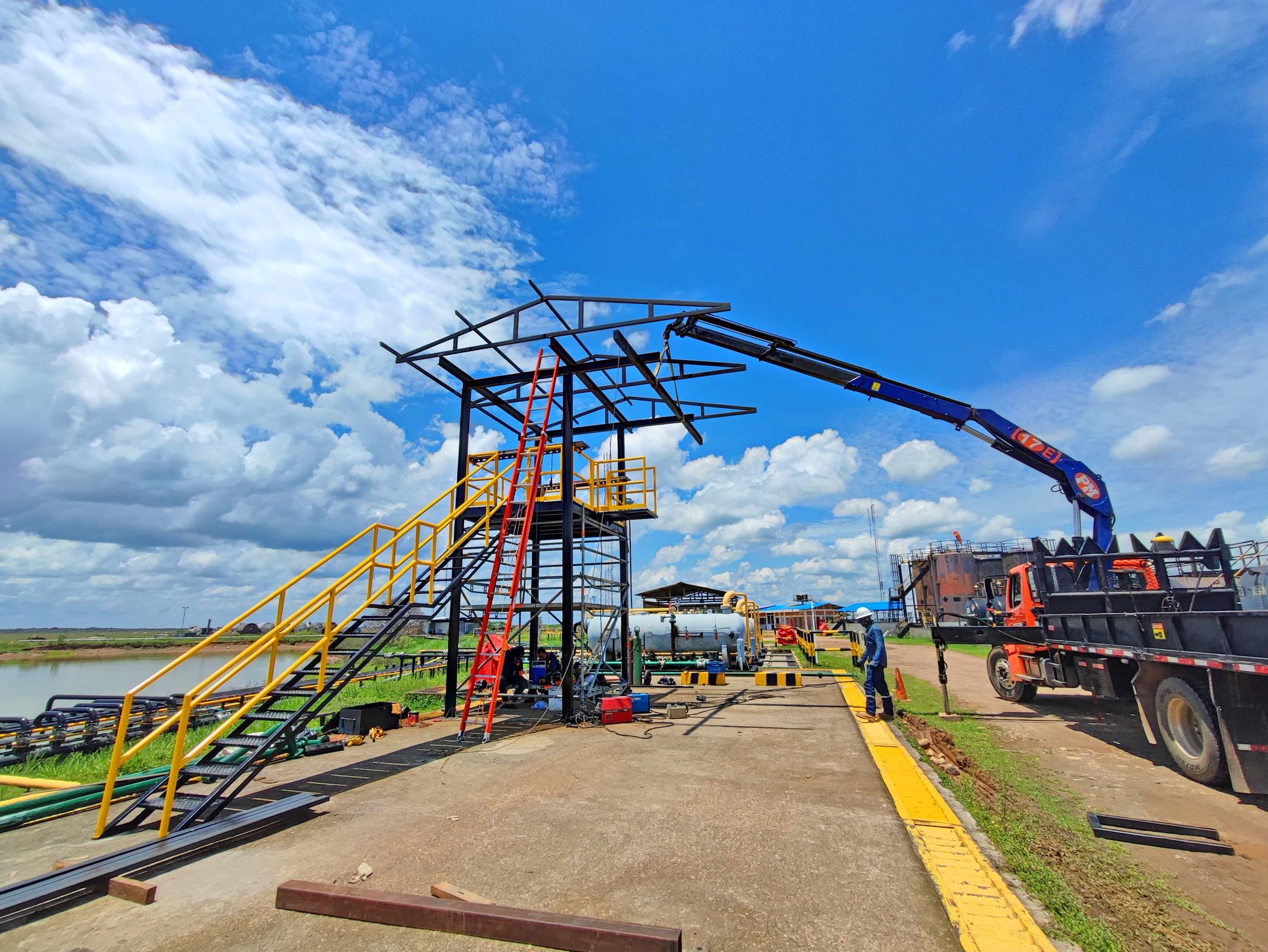 Estructura de cargadero en construcción sobre una plataforma industrial, con grúa de montaje y personal de Eccosis trabajando en el sitio.